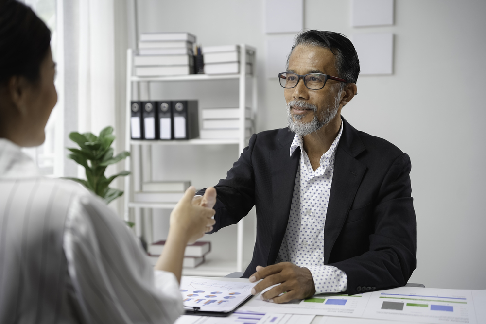 senior manager and young female professional shaking hands in a bright office during a business meeting